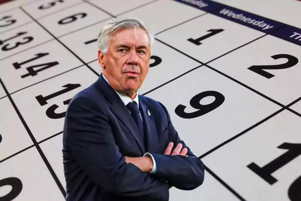 Un hombre de traje con los brazos cruzados frente a un calendario.