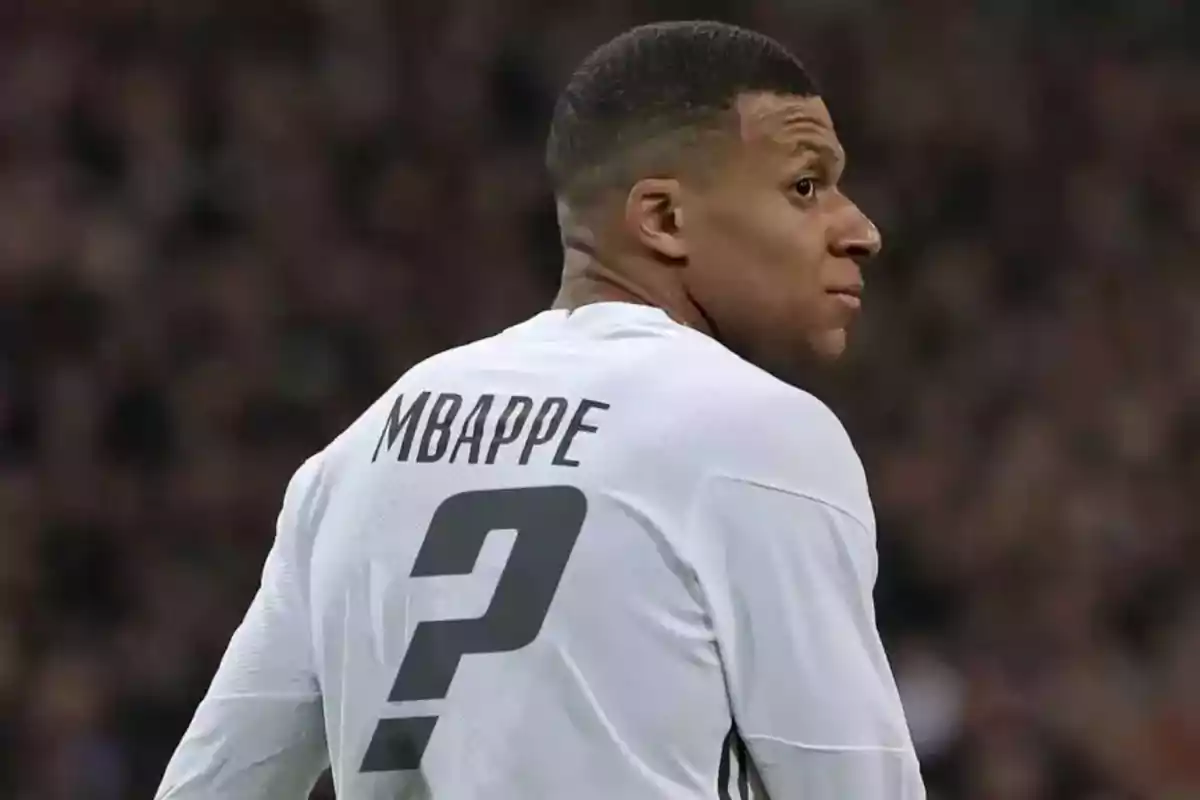 Jugador de fútbol con camiseta blanca que tiene el nombre "MBAPPE" y un signo de interrogación en la espalda.