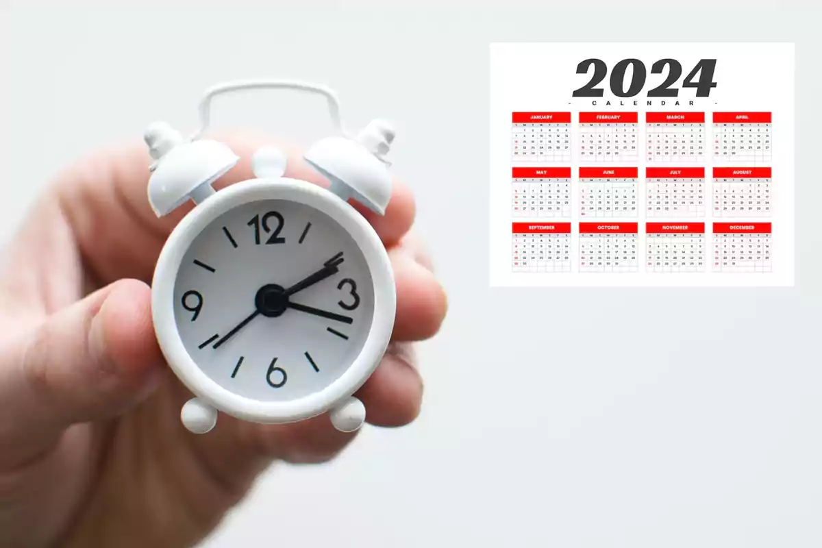 Un reloj despertador blanco en una mano junto a un calendario del año 2024.