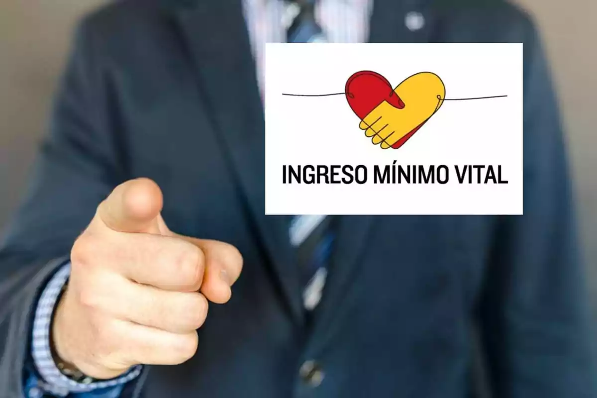 Una persona en traje señalando con el dedo índice hacia adelante, con un cartel que muestra un corazón dividido en dos colores y el texto "INGRESO MÍNIMO VITAL".