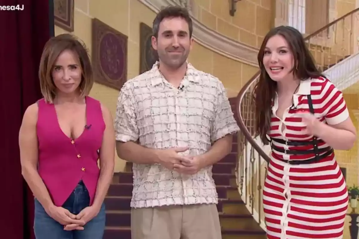 Tres personas posan sonrientes en un set de televisión con una escalera de fondo Tres personas posan sonrientes en un set de televisión con una escalera de fondo