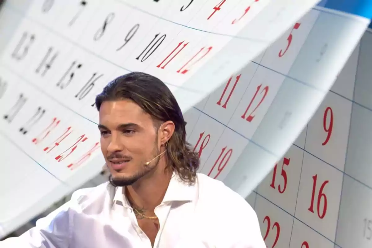 Un hombre con camisa blanca y micrófono en la oreja frente a un fondo de calendario.