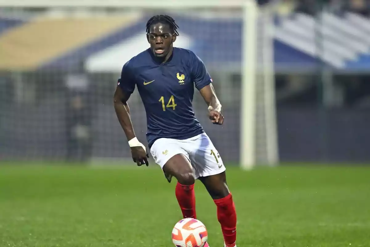 Jugador de fútbol con el uniforme de la selección de Francia corriendo con el balón en el campo.