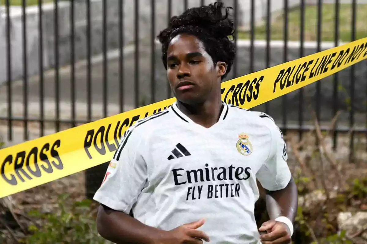 Jugador de fútbol con camiseta del Real Madrid corriendo frente a una cinta de advertencia de la policía.