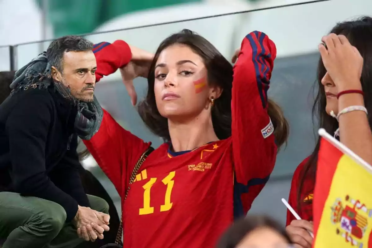 Una mujer con la camiseta de la selección española de fútbol y la bandera pintada en la mejilla, junto a un hombre con bufanda y chaqueta oscura.