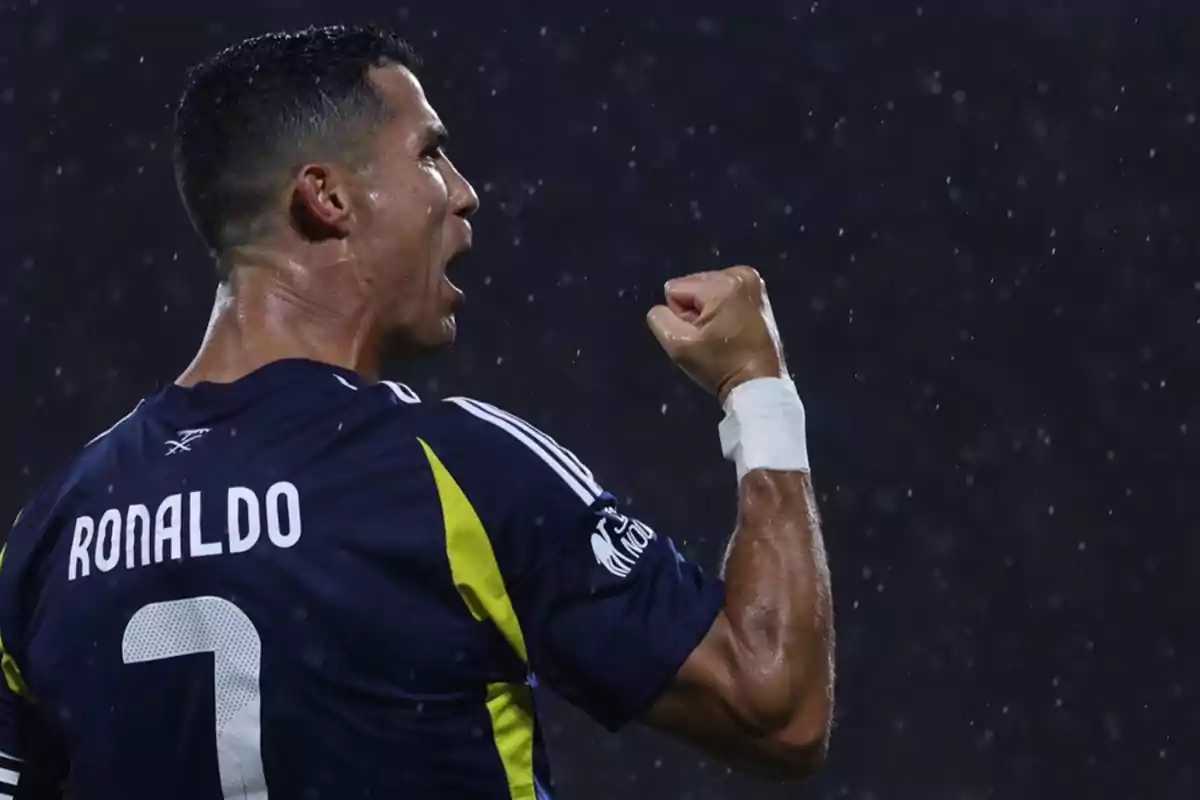 Un jugador de fútbol celebrando con el puño en alto bajo la lluvia, con el nombre "Ronaldo" y el número 7 en su camiseta.