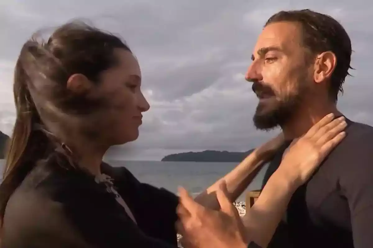 Una mujer y un hombre se miran de cerca en una playa con el mar y el cielo nublado de fondo. Una mujer y un hombre se miran de cerca en una playa con el mar y el cielo nublado de fondo.