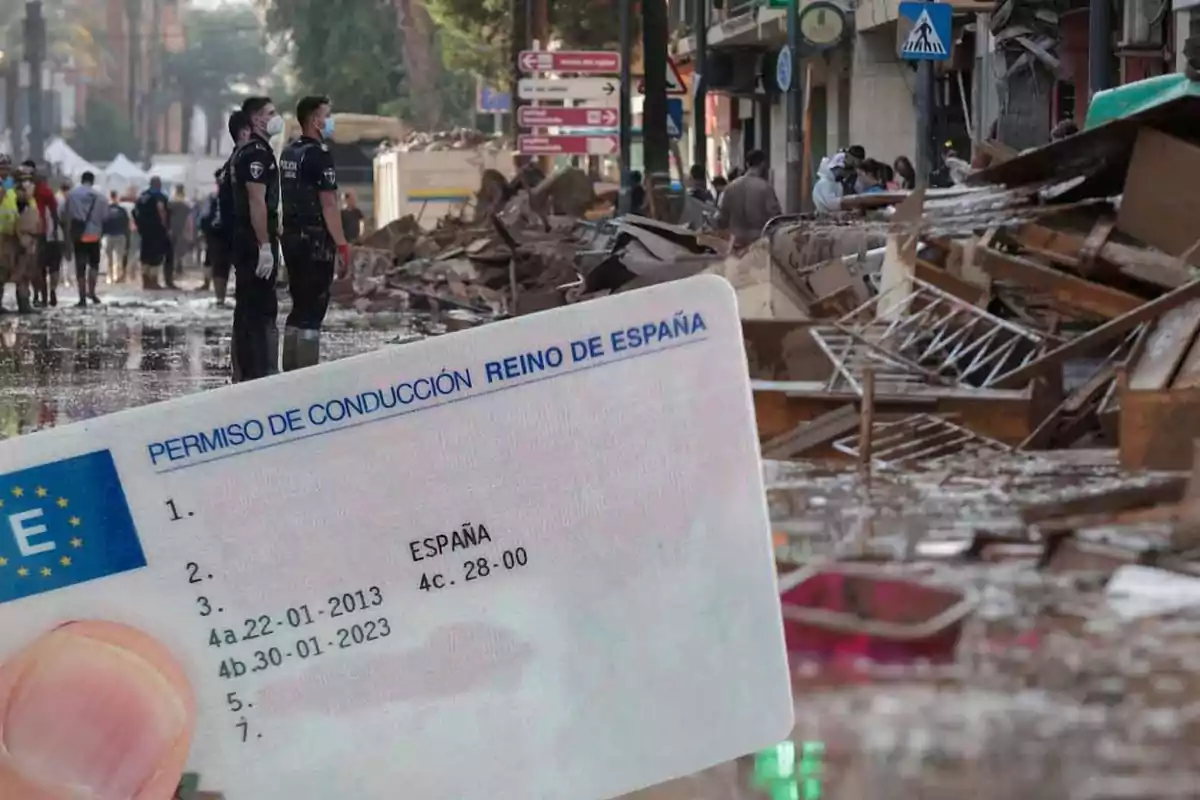 Una calle inundada con escombros y personas trabajando en el fondo mientras un permiso de conducción de España se muestra en primer plano.