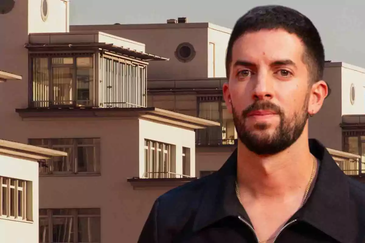 Un hombre con barba y cabello corto está de pie frente a un edificio moderno con grandes ventanas.