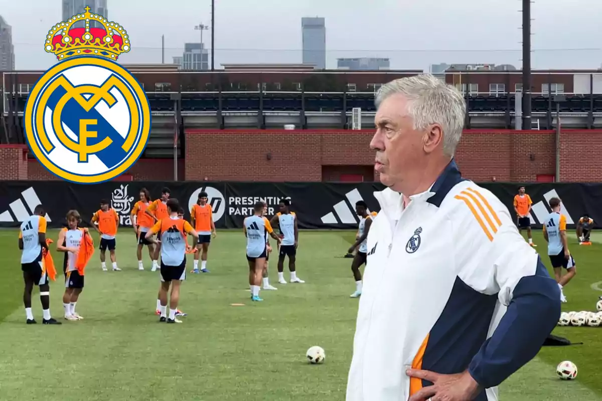 Un entrenador de fútbol observa a sus jugadores durante una sesión de entrenamiento en un campo, con el logo del Real Madrid en la esquina superior izquierda.