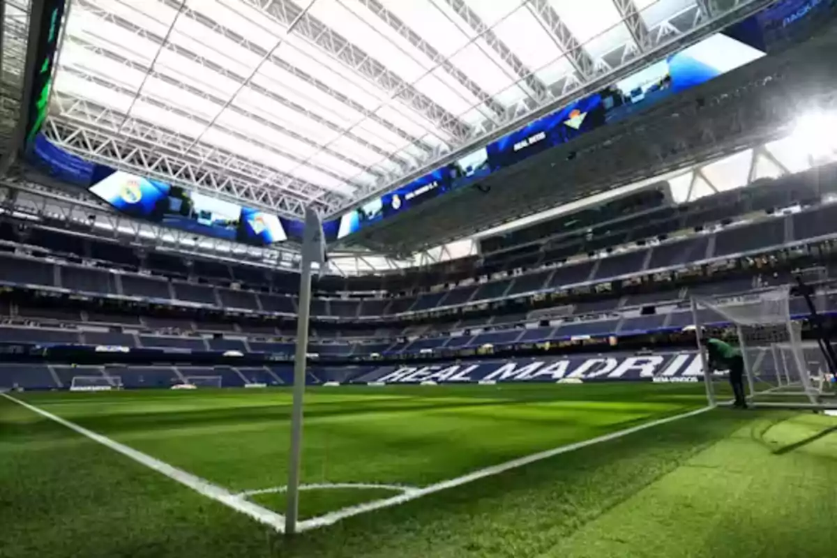 Estadio de fútbol con techo retráctil y gradas vacías, con el nombre "Real Madrid" visible en las gradas.