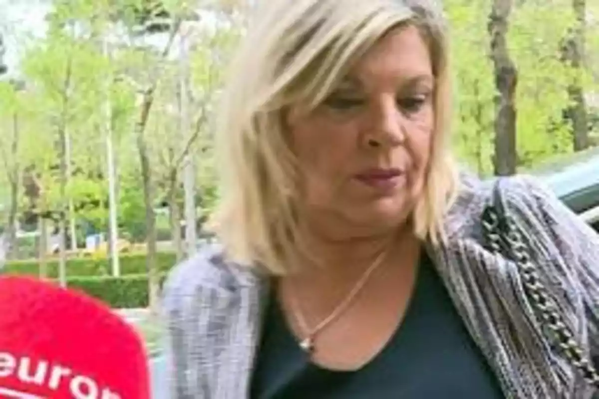 Mujer rubia con chaqueta gris y camiseta negra siendo entrevistada al aire libre. Mujer rubia con chaqueta gris y camiseta negra siendo entrevistada al aire libre.