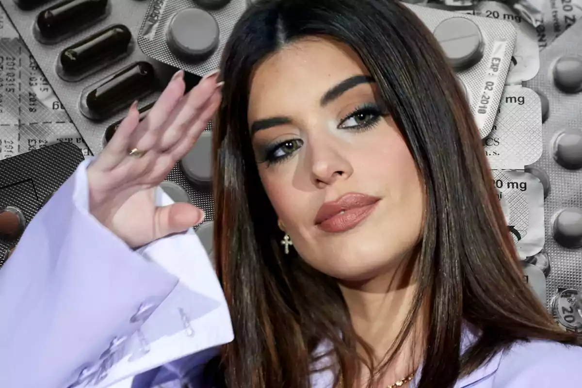 Una mujer con cabello oscuro y maquillaje elegante levanta la mano frente a un fondo de blísteres de pastillas.