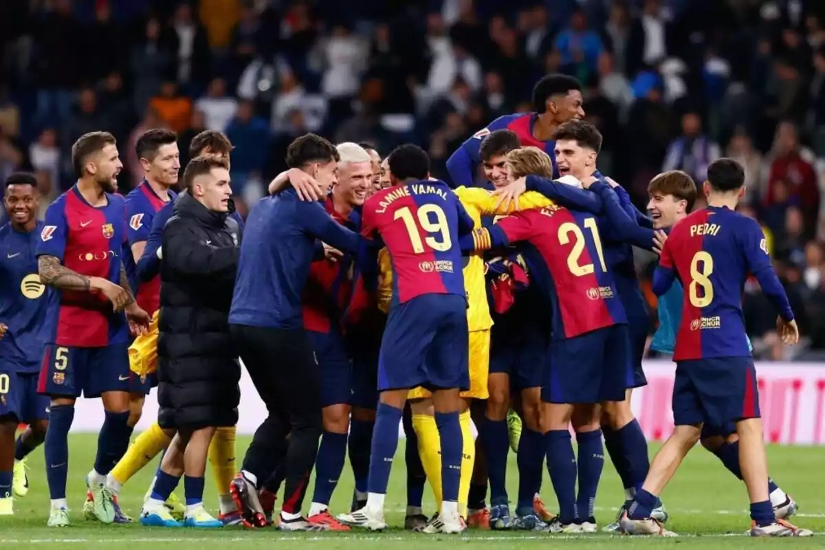 Un grupo de jugadores de fútbol celebrando en el campo con uniformes azul y rojo.