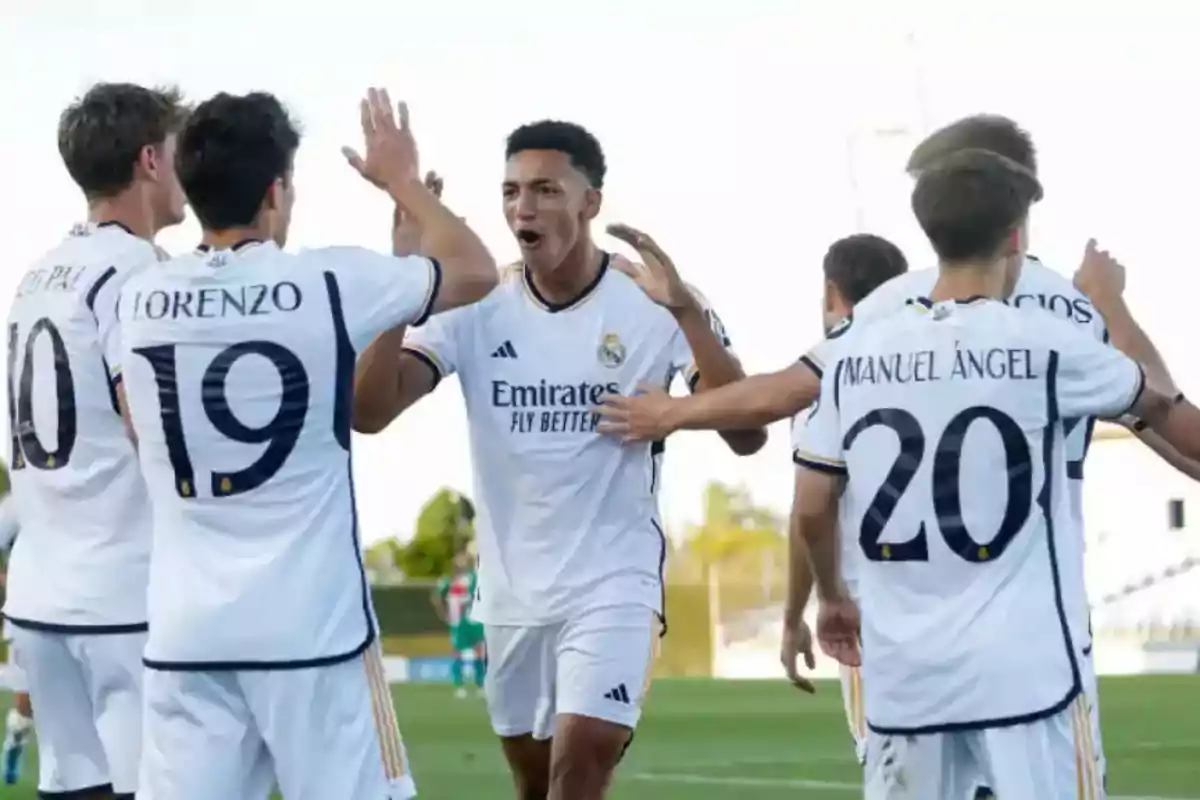 Cantera del Real Madrid celebrando un gol en el campo con uniformes blancos del Real Madrid.