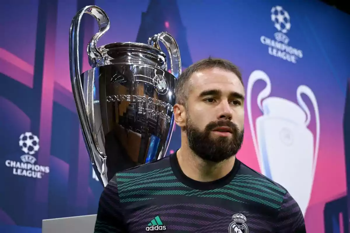 Un jugador de fútbol del Real Madrid posa junto al trofeo de la UEFA Champions League.