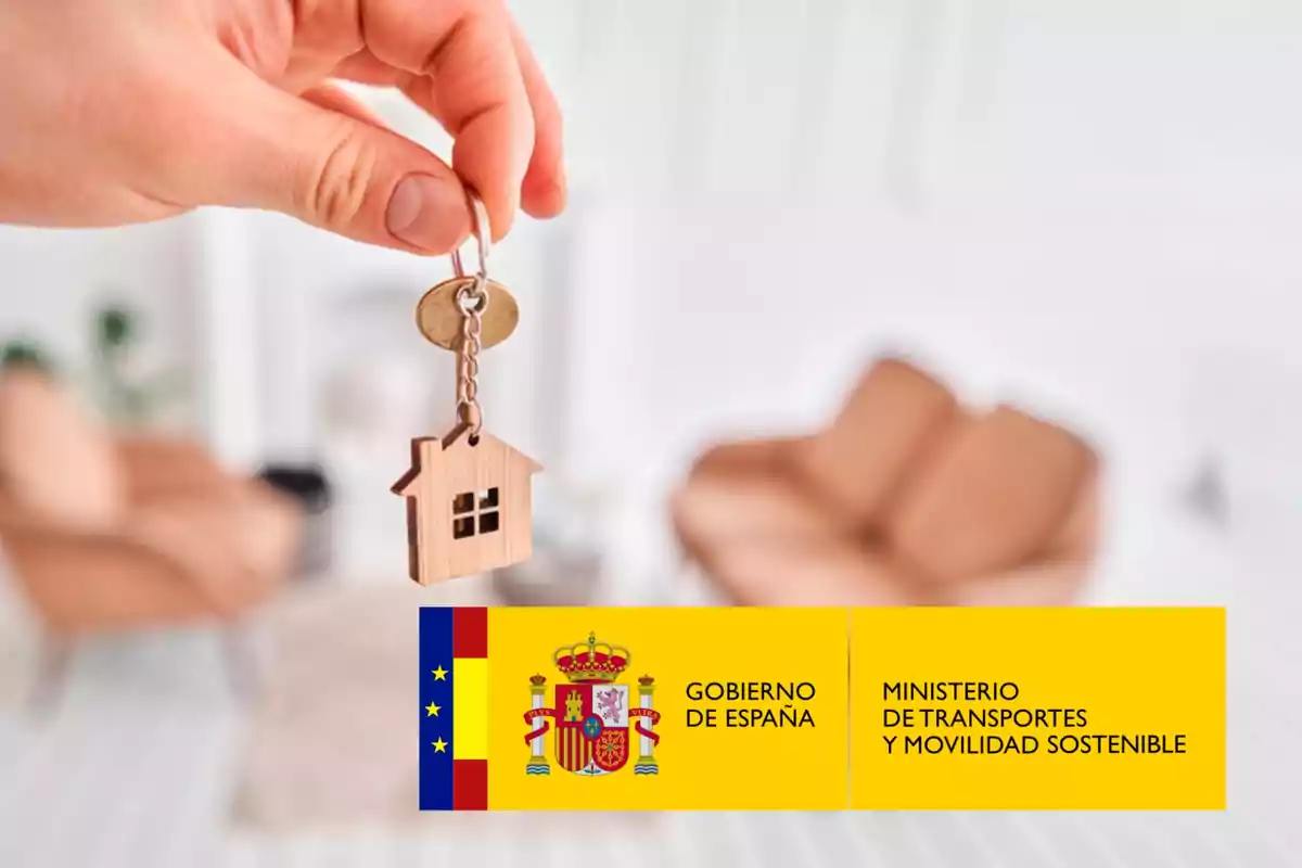 Una mano sosteniendo una llave con un llavero en forma de casa, con el logotipo del Gobierno de España y el Ministerio de Transportes y Movilidad Sostenible en la parte inferior derecha.