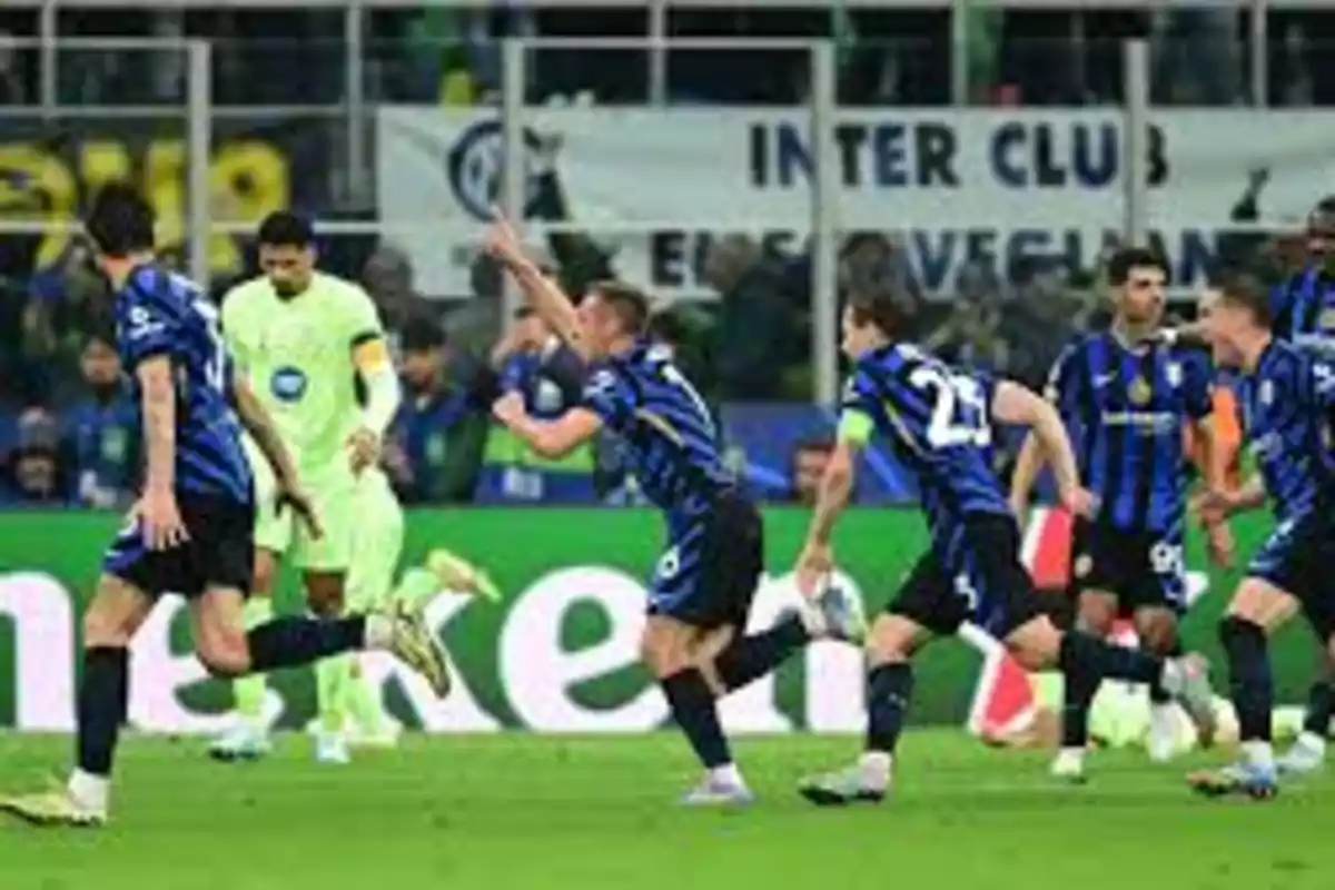Jugadores de fútbol en uniforme azul y negro celebran en el campo durante un partido. Jugadores de fútbol en uniforme azul y negro celebran en el campo durante un partido.
