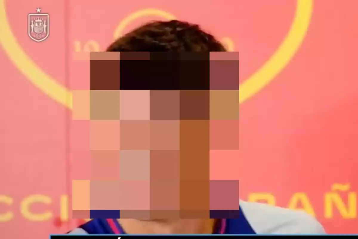 Una persona con la cara pixelada frente a un fondo rojo con el escudo de la selección española.