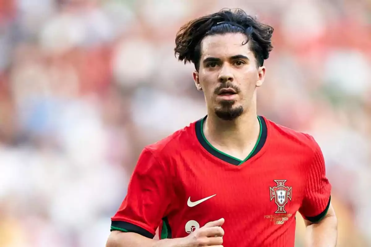 Jugador de fútbol con camiseta roja de la selección de Portugal en el campo de juego. Jugador de fútbol con camiseta roja de la selección de Portugal en el campo de juego.