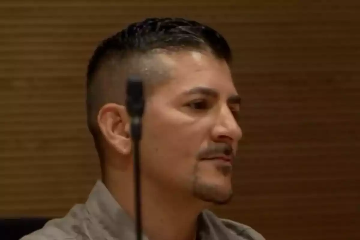 Un hombre con barba y cabello corto está sentado en un entorno interior. Un hombre con barba y cabello corto está sentado en un entorno interior.
