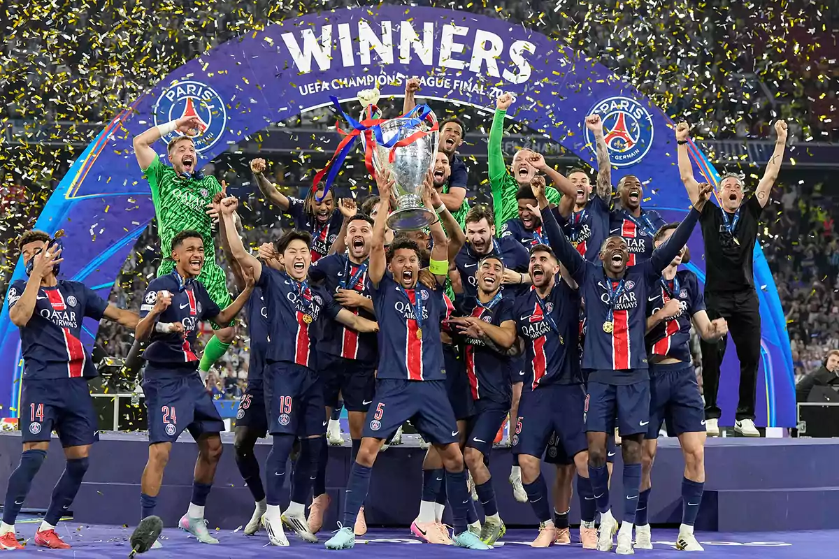 Jugadores de un equipo de fútbol celebran eufóricos levantando un trofeo de la Champions League mientras cae confeti dorado en el estadio