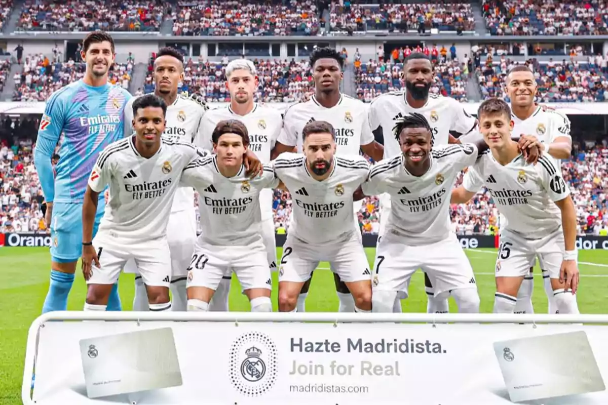 Jugadores del Real Madrid posando para una foto de equipo en el estadio antes de un partido, con un cartel promocional de "Hazte Madridista" en la parte inferior.