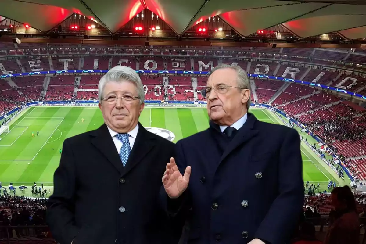 Dos hombres de traje oscuro posan frente a un estadio de fútbol con gradas rojas y blancas.