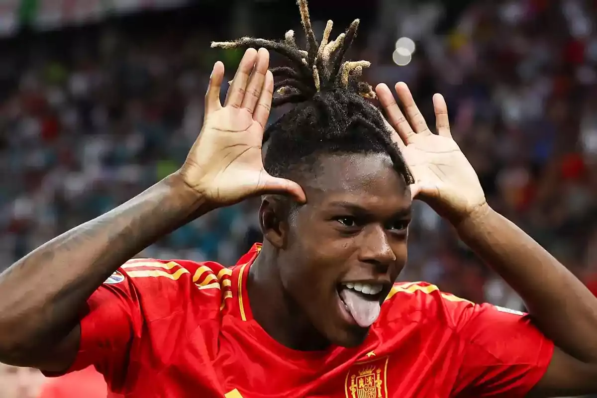 Jugador de fútbol con la camiseta de España celebrando con un gesto divertido.