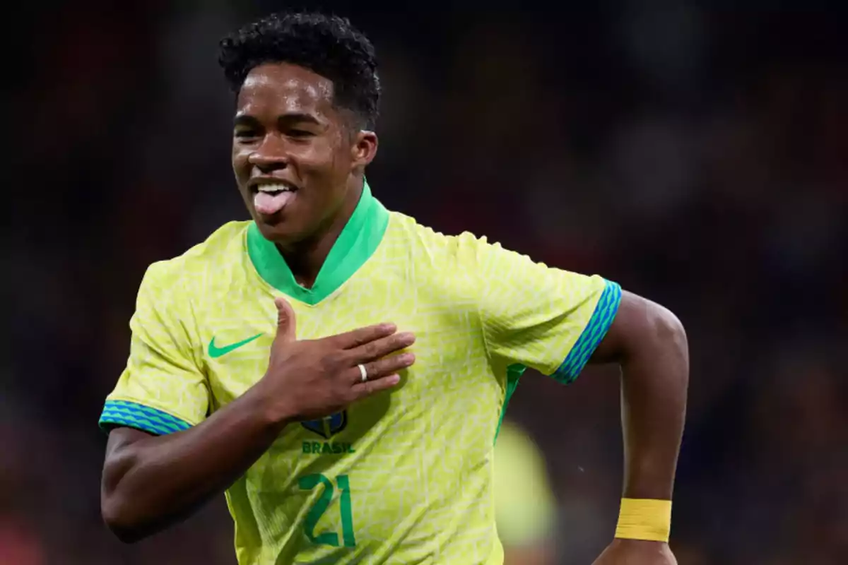 Un jugador de fútbol con la camiseta de Brasil celebra con la mano en el pecho y la lengua afuera.