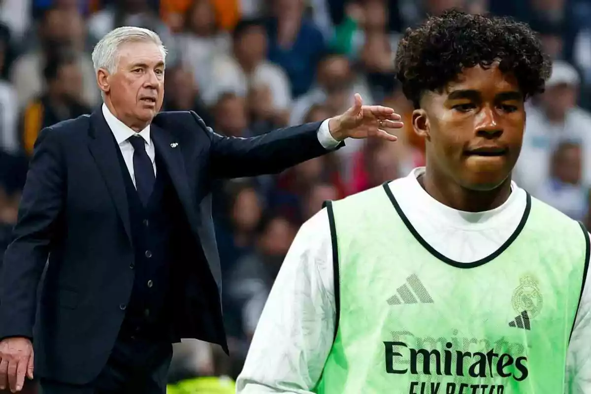 Un entrenador de fútbol da instrucciones mientras un jugador con peto observa en el campo.