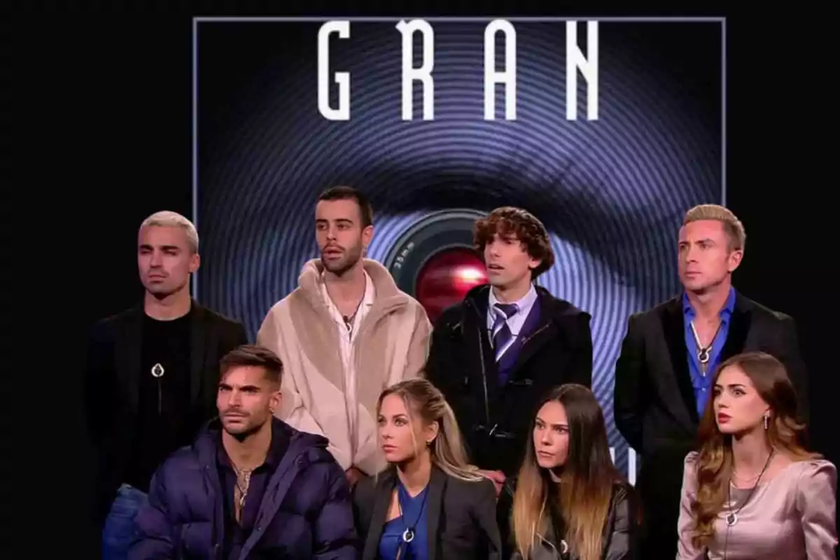 Un grupo de personas sentadas y de pie frente a un fondo oscuro con la palabra "GRAN" en la parte superior.