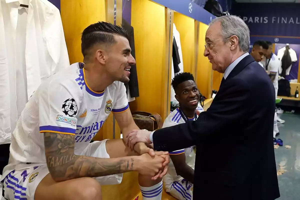 Jugadores de fútbol en el vestuario conversando con un hombre mayor.