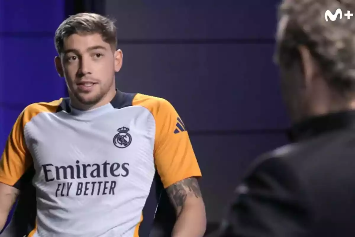 Un jugador de fútbol con el uniforme del Real Madrid está siendo entrevistado en un estudio de televisión.