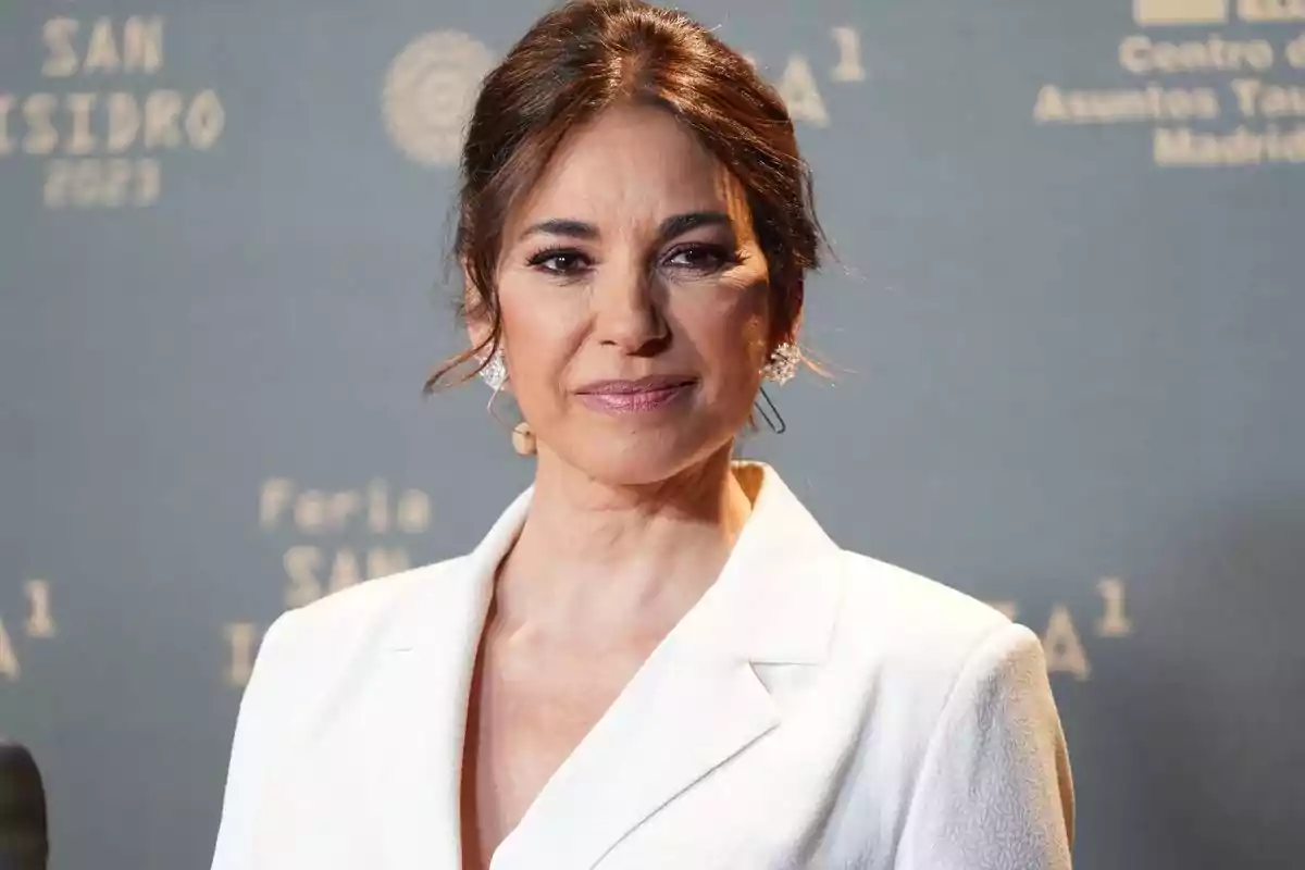 Mujer con traje blanco en un evento con fondo gris. Mujer con traje blanco en un evento con fondo gris.