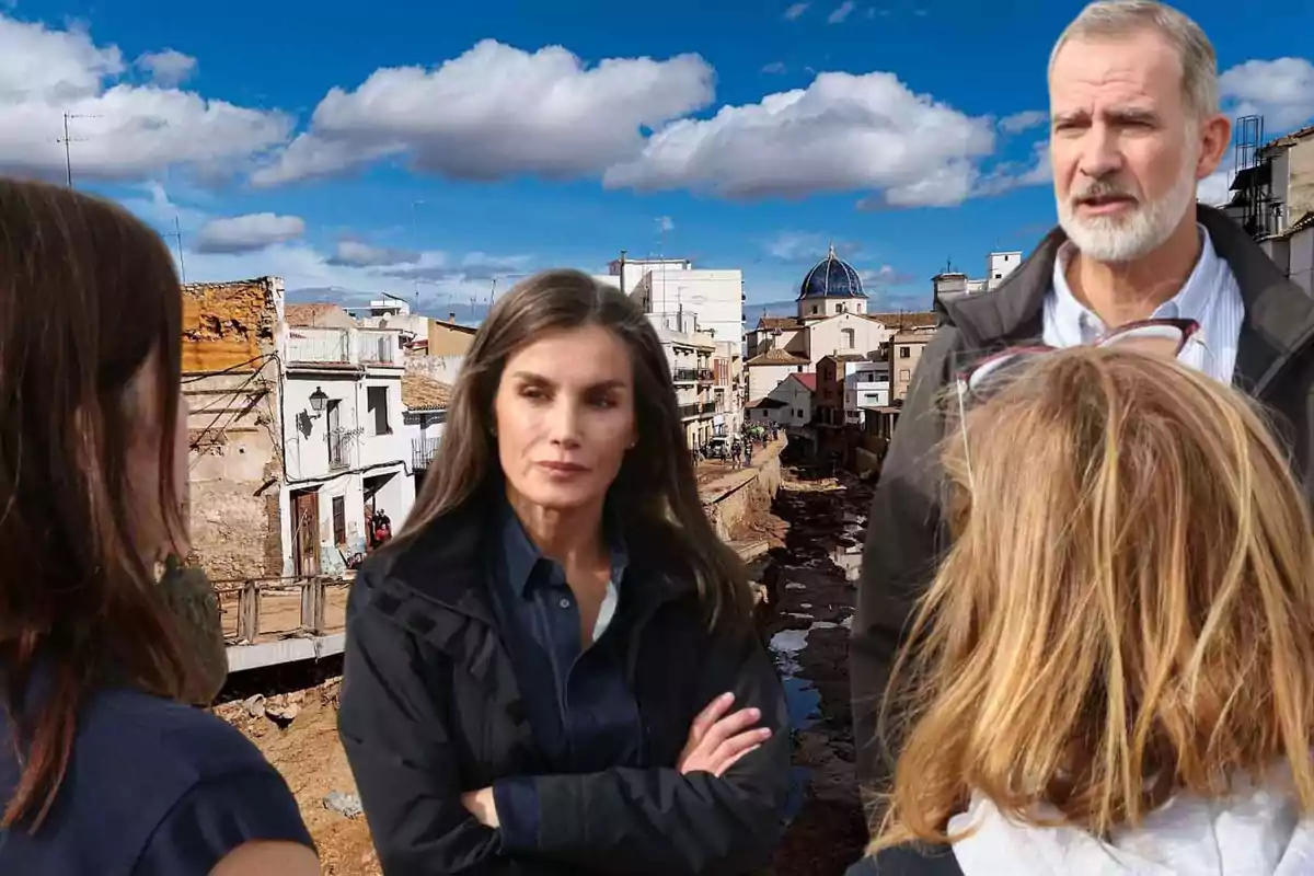 Un grupo de personas conversa en una zona urbana afectada por un desastre natural, con edificios dañados y un cielo parcialmente nublado al fondo.