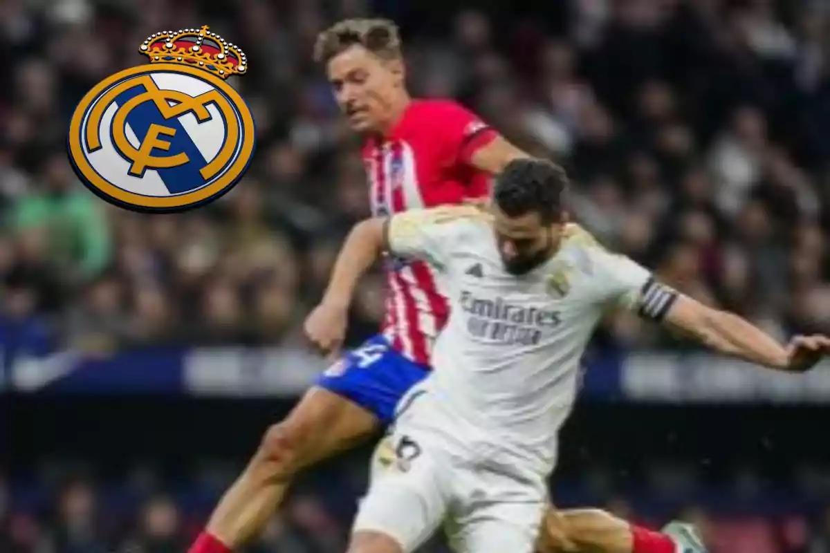 Dos jugadores de fútbol compiten por el balón durante un partido, uno con uniforme blanco y el otro con uniforme rojo y blanco, mientras el escudo del Real Madrid aparece en la esquina superior izquierda.