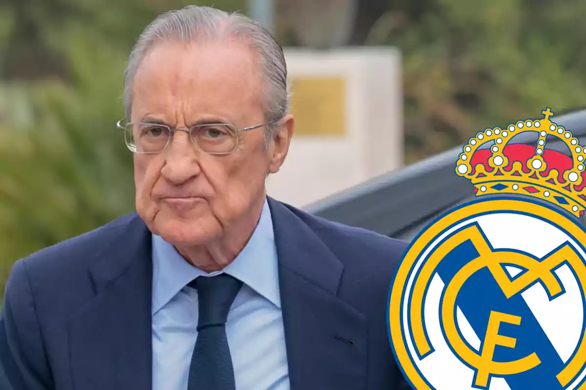 Hombre con traje azul y corbata, junto al escudo del Real Madrid.