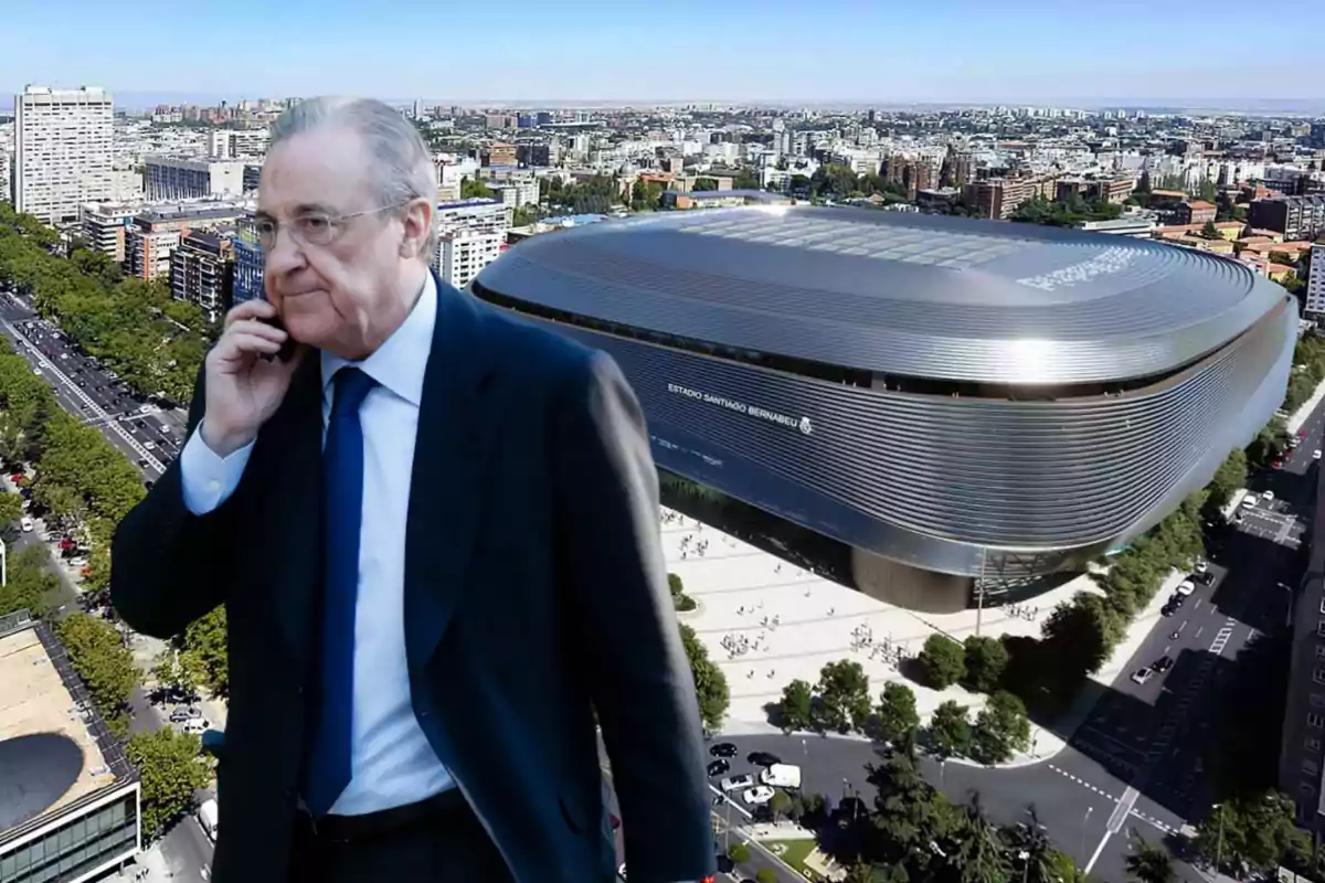 Un hombre de traje hablando por teléfono frente a un estadio moderno en una ciudad.