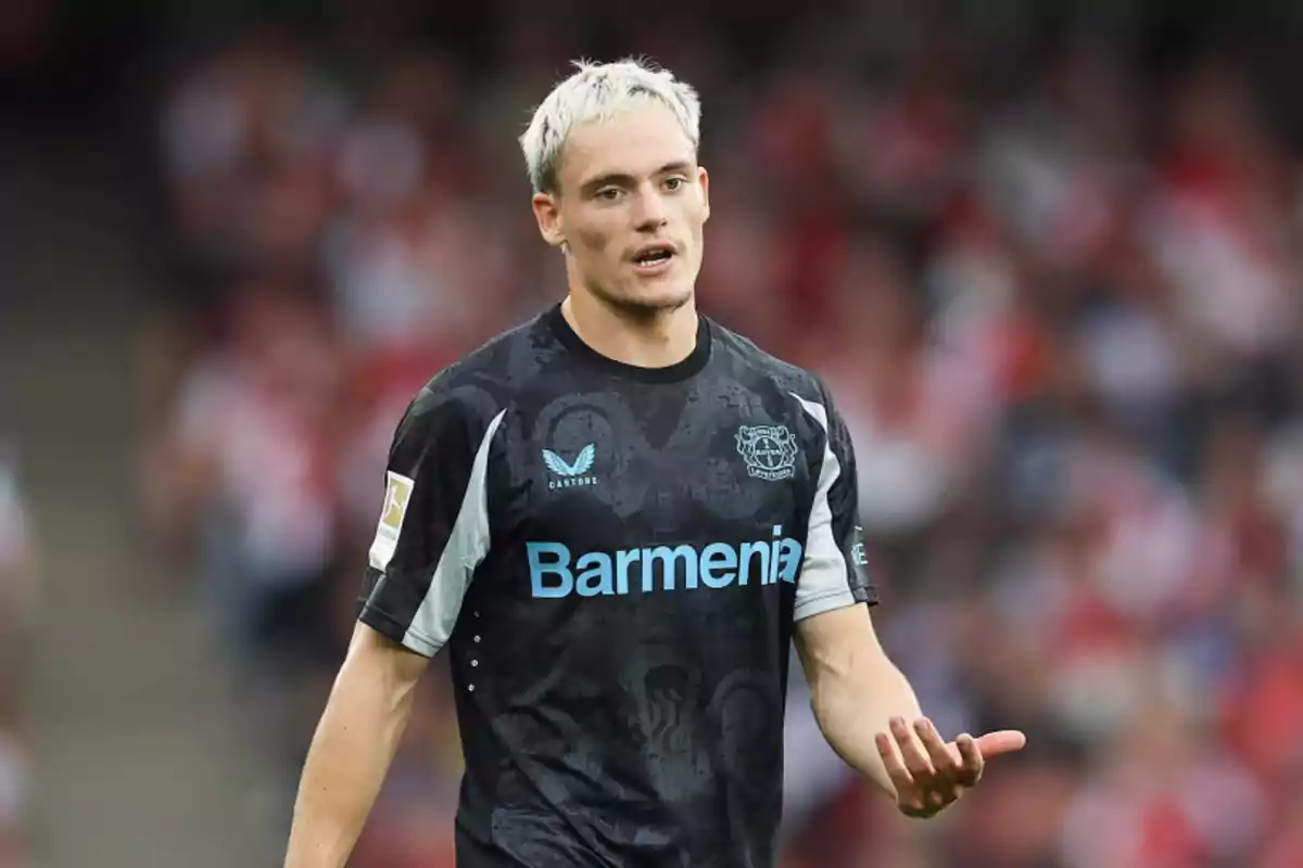 Jugador de fútbol con camiseta negra del Bayer Leverkusen en el campo.