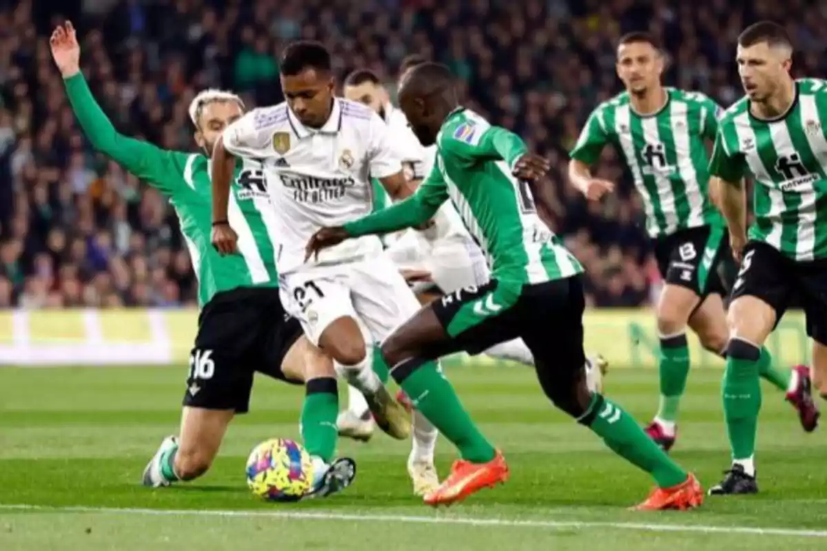 Jugadores de fútbol de dos equipos compiten por el balón en un partido.