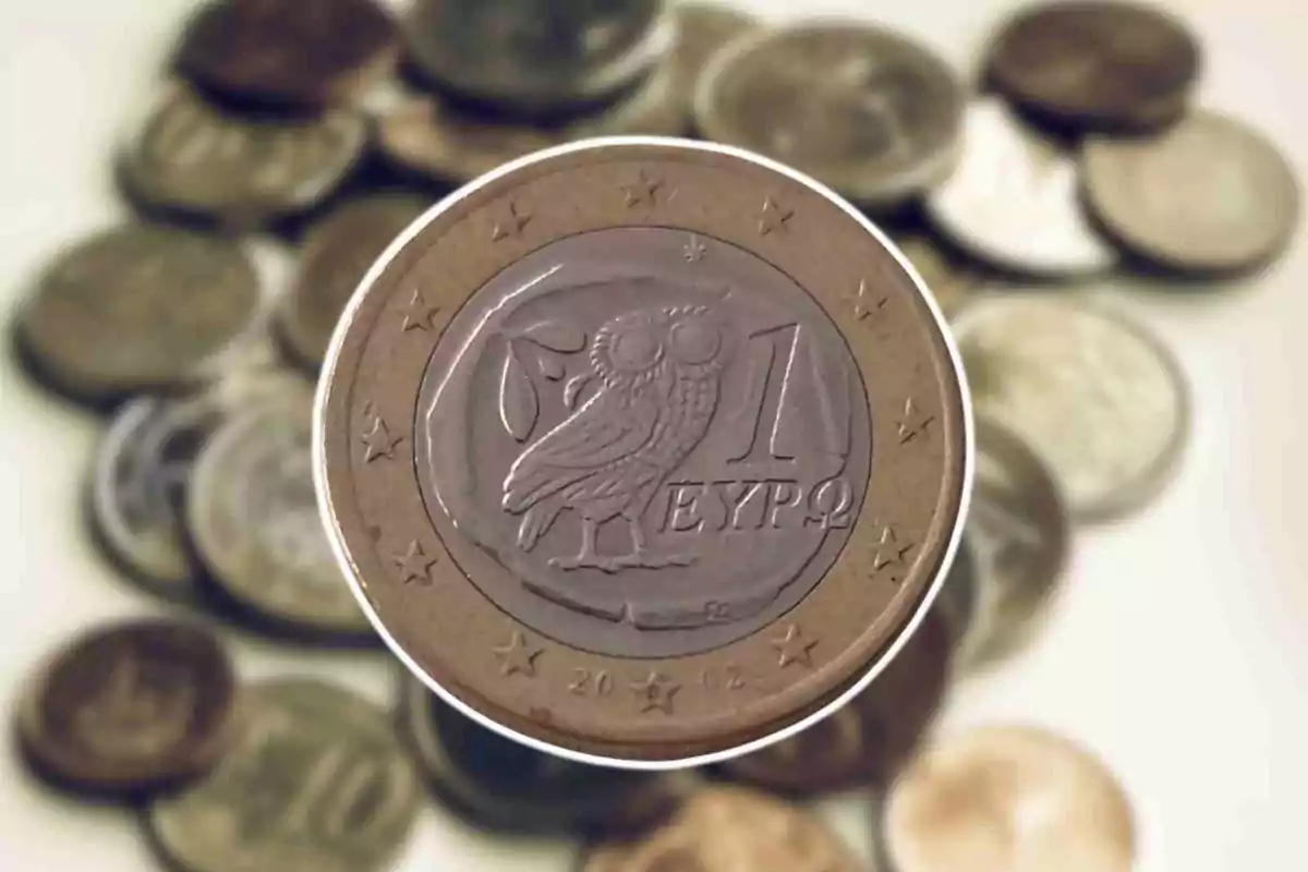 Una moneda de 1 euro con un búho en el centro y varias monedas desenfocadas en el fondo.