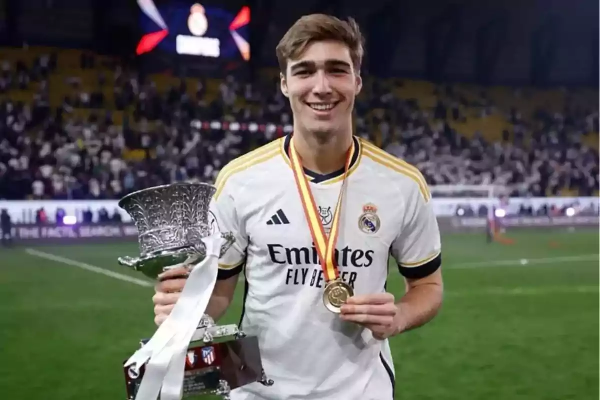 Jugador de fútbol del Real Madrid celebrando con un trofeo y una medalla en el campo de juego. Jugador de fútbol del Real Madrid celebrando con un trofeo y una medalla en el campo de juego.