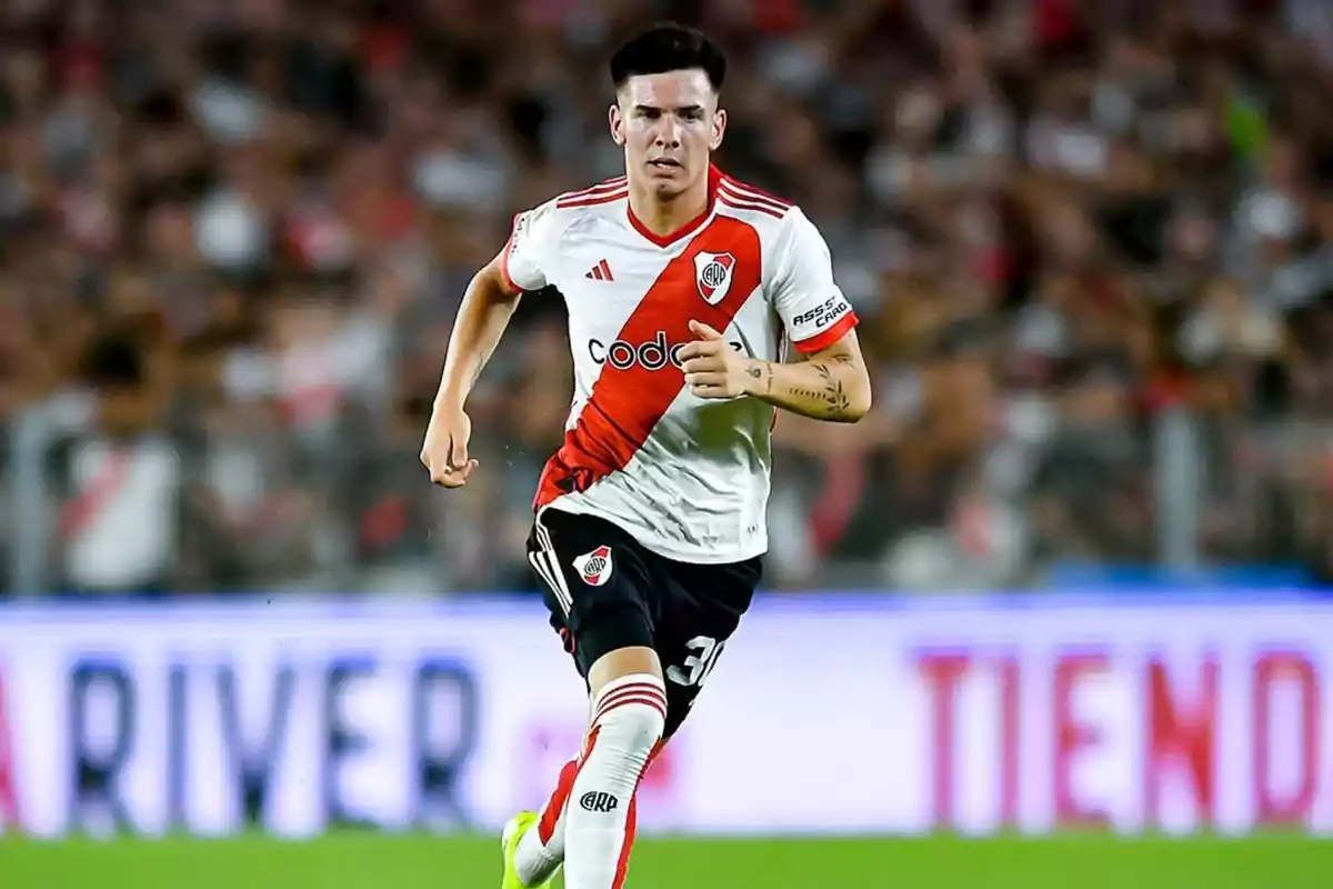 Jugador de fútbol corriendo en el campo con la camiseta de River Plate.