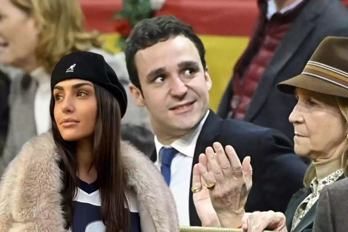 Un grupo de personas en un evento, una mujer con boina negra y abrigo de piel, un hombre con traje y corbata azul, y otra mujer con sombrero marrón.