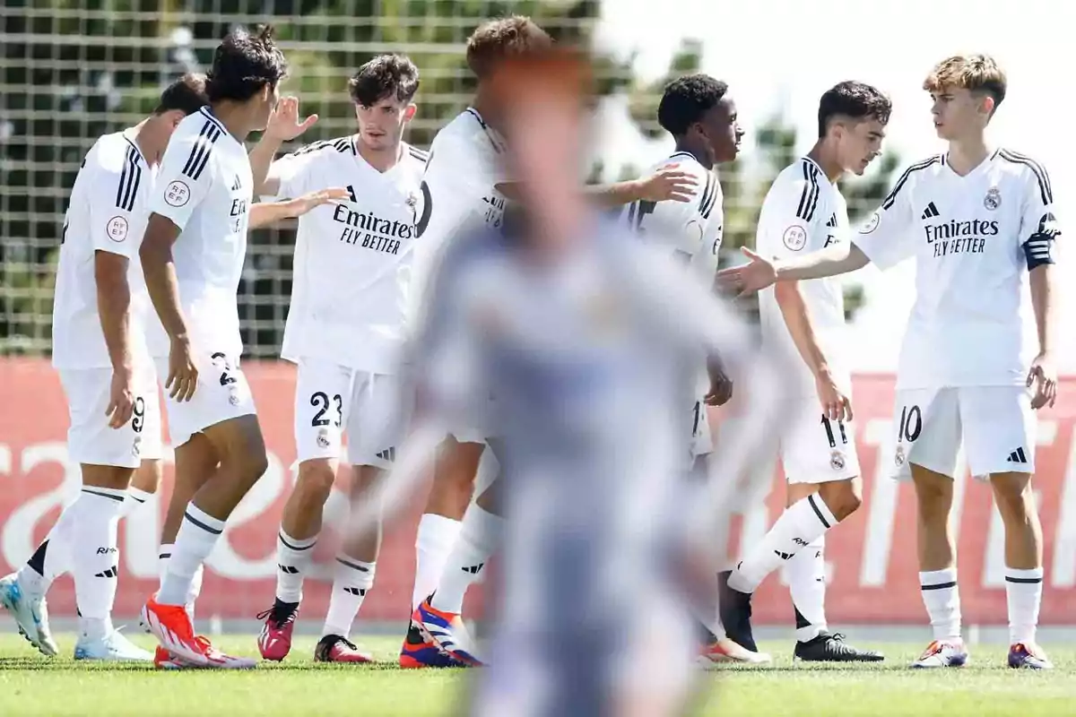 Jugadores de fútbol con uniformes blancos celebran en el campo.