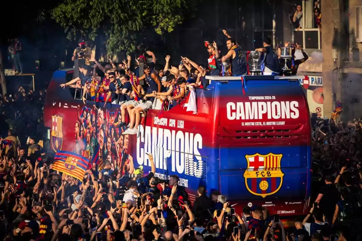Un autobús descapotable lleno de personas celebrando un campeonato, rodeado de una multitud de aficionados con banderas y camisetas del FC Barcelona. Un autobús descapotable lleno de personas celebrando un campeonato, rodeado de una multitud de aficionados con banderas y camisetas del FC Barcelona.