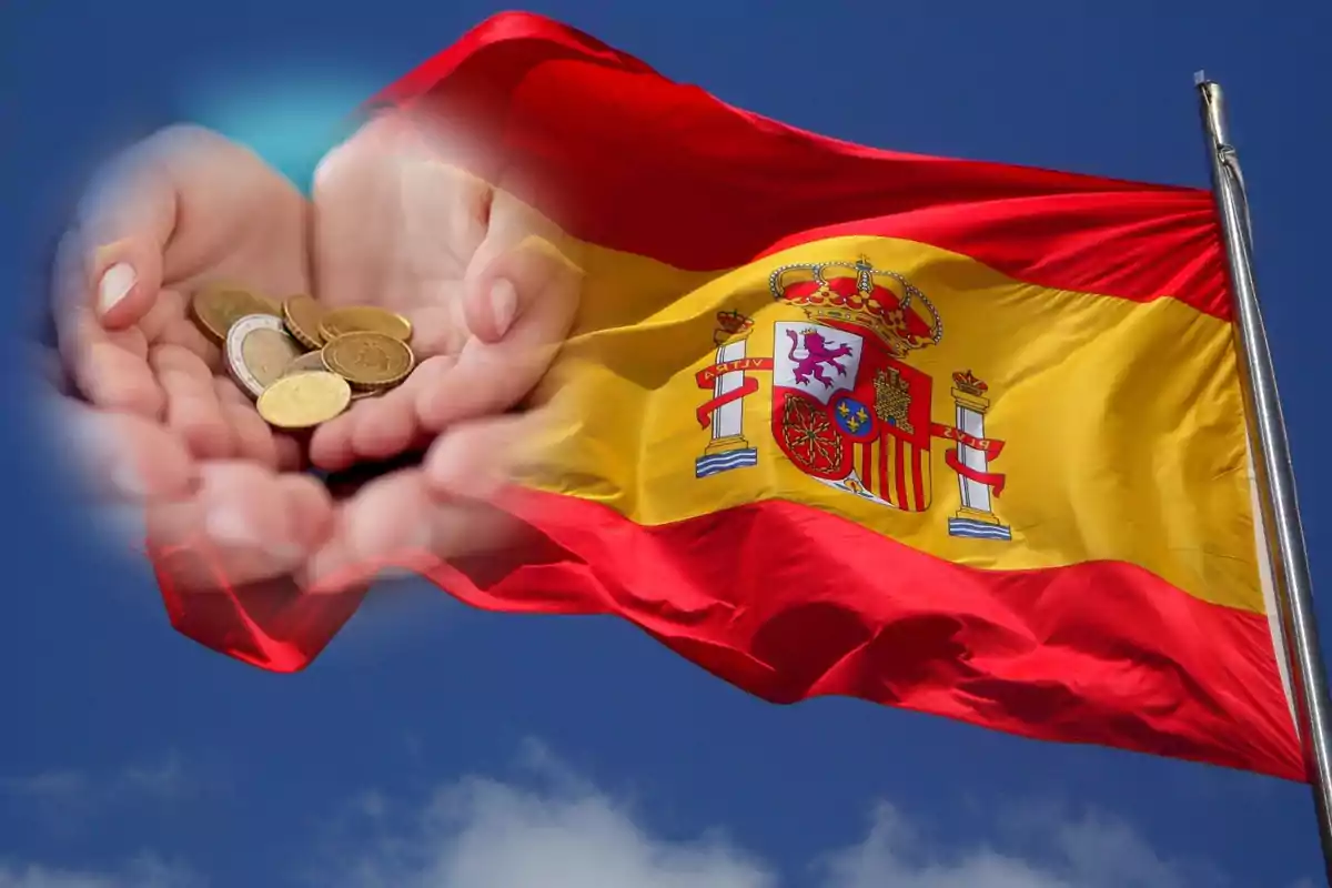 Manos sosteniendo monedas superpuestas sobre la bandera de España ondeando.