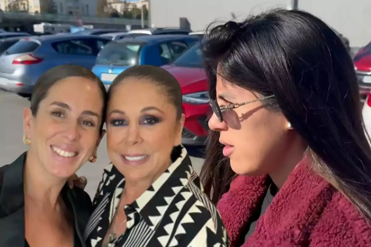 Tres mujeres posan juntas en un estacionamiento lleno de autos.