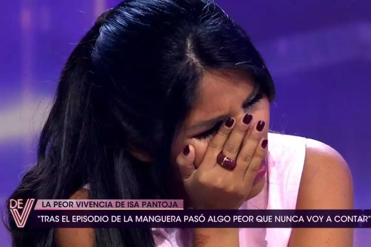 Una persona con cabello oscuro se cubre el rostro con la mano en un programa de televisión, mostrando una expresión de emoción intensa.